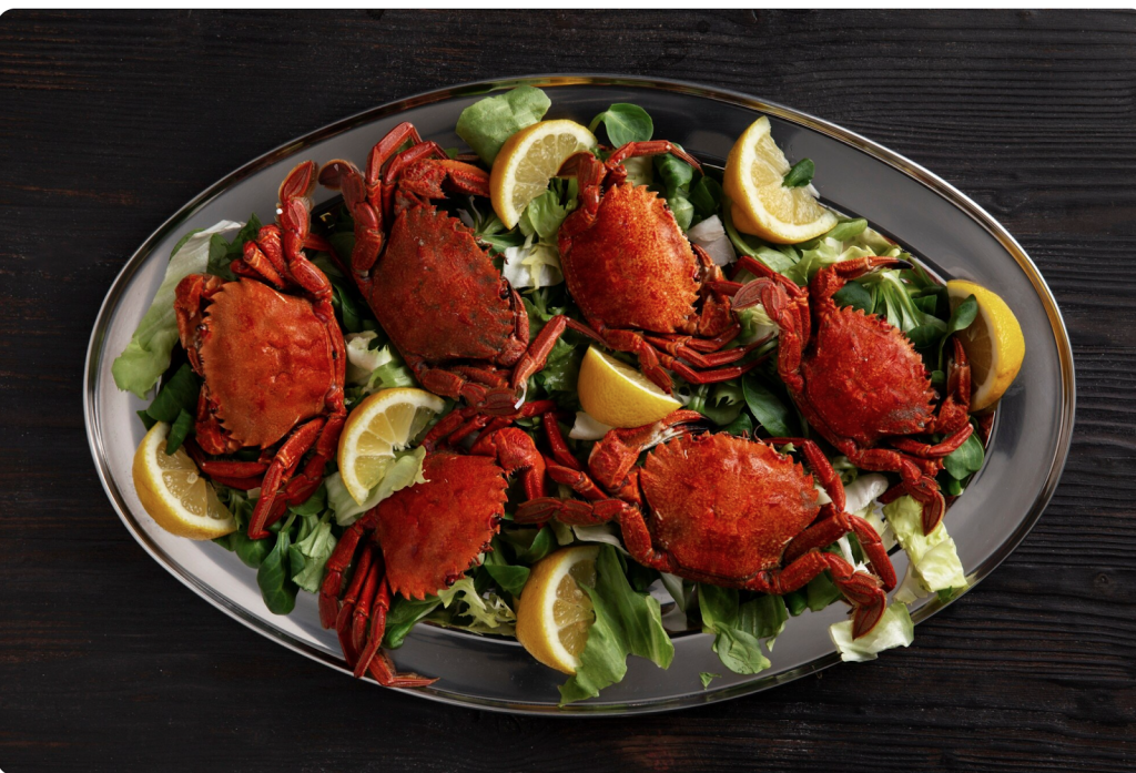 boiled red crab on a plate with salad and lemon garnish