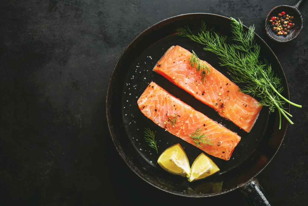 two fillets of salmon in a small pan with lemon garnish