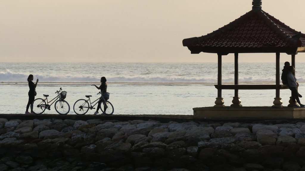 People relaxing around a yurt overlooking Sanur's ocean