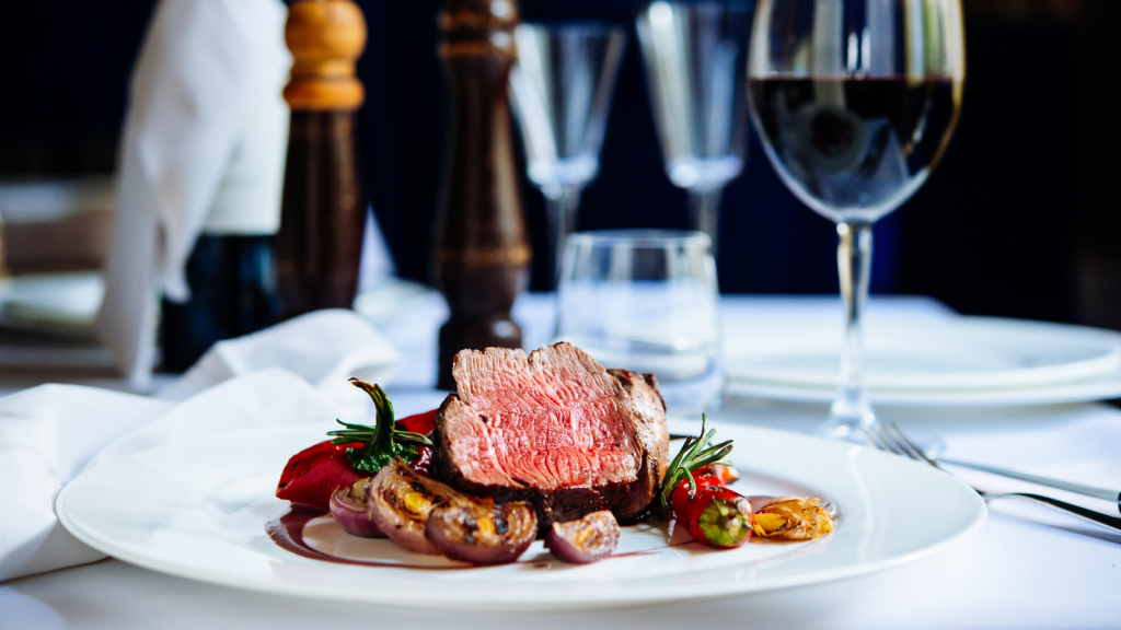 A meal of steak and vegetables and a glass of red wine from a steakhouse