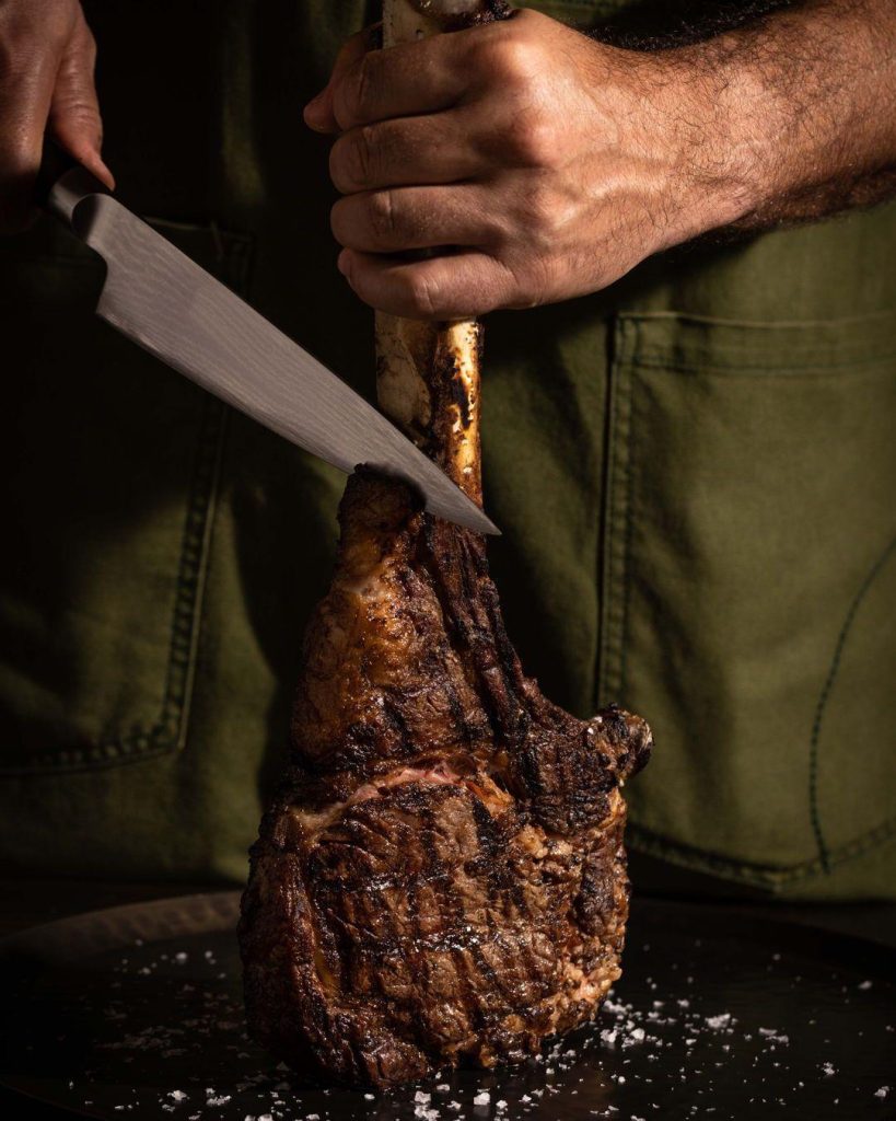 A person carving a large piece of steak
