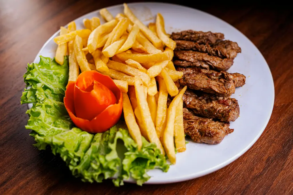 Sliced meat, french fries and side salad on a plate