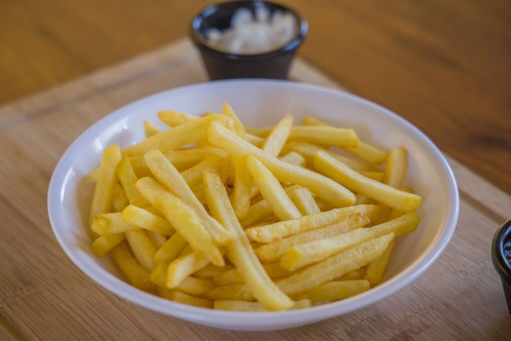 A bowl of french fries with a side sauce